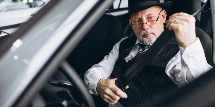 Літній чоловік в капелюсі та окулярах пристібає ремінь безпеки в автомобілі - - Moja Polska
